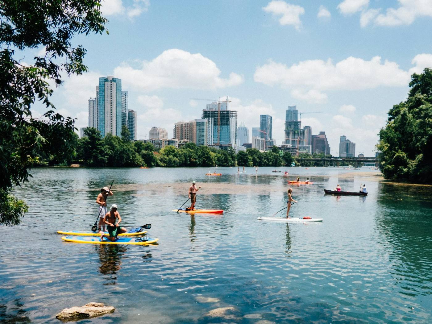 Paddleboarders on Lady Bird Lake with the downtown Austin skyline behind them